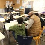 A teacher and students sit together in a classroom talking