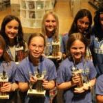 Seven students stand holding their Global Reading Challenge trophies with their teacher.